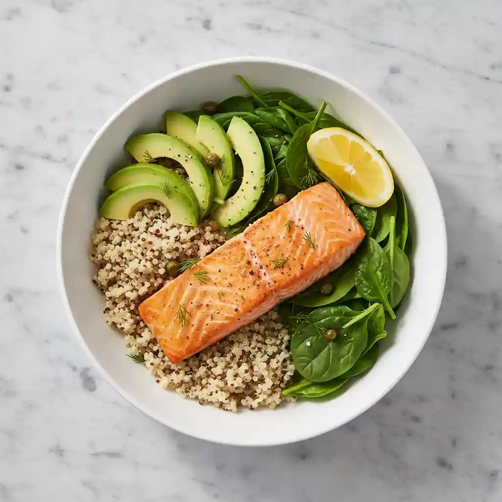 Top-down view of a roasted salmon bowl with avocado, quinoa, and lemon, representing a healthy lunch for focus.